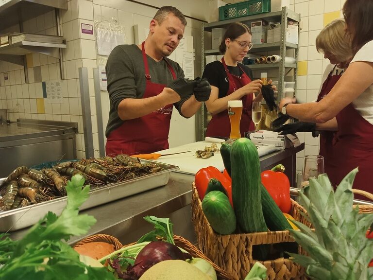 Koch bereitet Meeresfrüchte in Küche mit frischem Gemüse und Getränken zu.