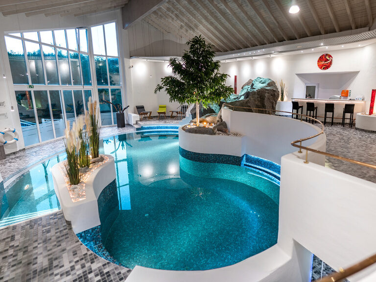 Modernes Spa mit Innenpool, Lounge-Bereich und warmem Lichtambiente.