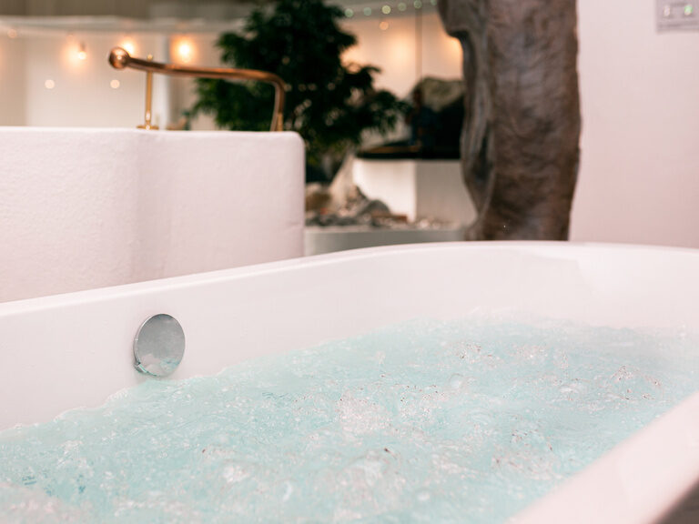 Sprudelbad im Spa-Bereich mit weißer Wanne und türkisfarbenem Wasser.