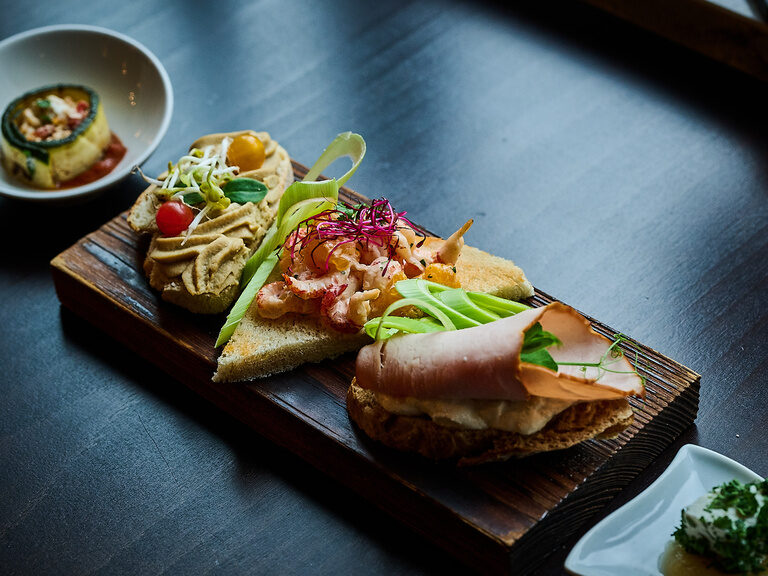 Bunte Vorspeisen auf Brot mit Hummus, Lachs, Schinken und Gemüse.