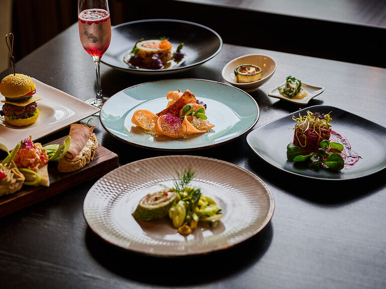 Vorspeisenvariation auf schwarzen und weißen Tellern, kunstvoll angerichtet mit Deko.