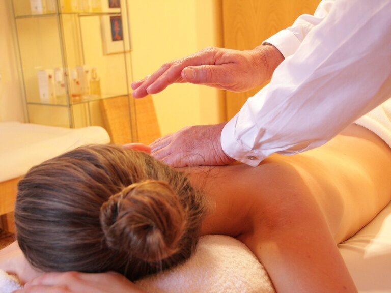 Therapeut massiert Rücken einer Frau in entspannter Spa-Atmosphäre.