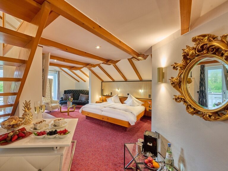 Gemütliche Suite mit Dachschrägen, Sitzecke, Holzbalken und Treppe zur Empore.