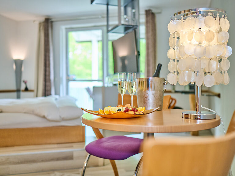 Detailaufnahme Tisch mit Champagner, Obstplatte und moderner Lampe.