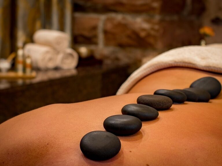 Rücken mit sieben warmen schwarzen Steinen bei entspannender Hot-Stone-Massage im Spa.