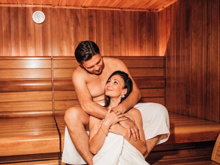 Zwei Personen stoßen mit Cocktails im am Pool des 4 Sterne Hotels im bayerischen Wald an.