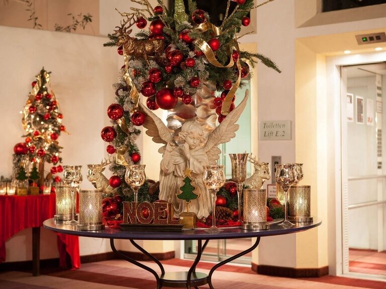 Festliche Weihnachtsdekoration mit Engel, Rentierfiguren und roten Kugeln.